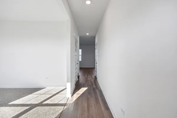 a view of a hallway with wooden floor and a carpet