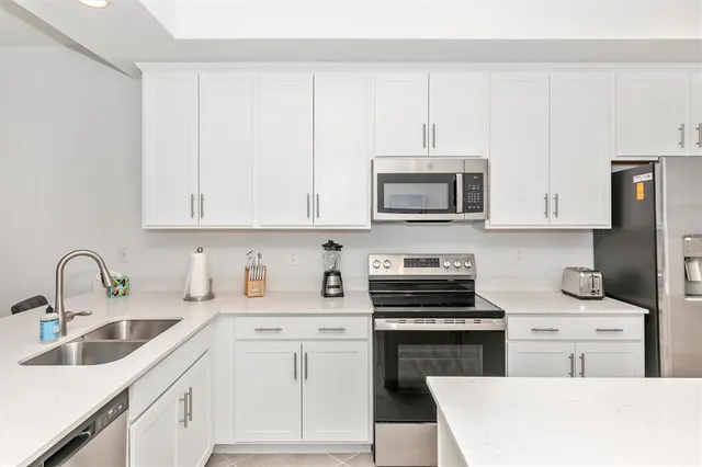 a kitchen with white cabinets and refrigerator