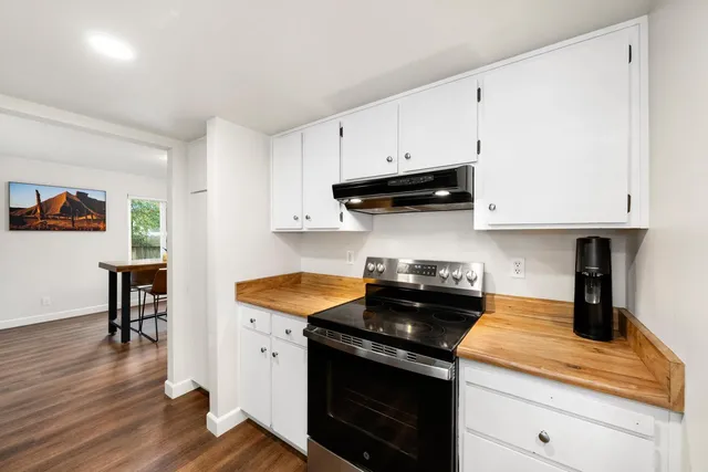 a kitchen with granite countertop white cabinets and black appliances