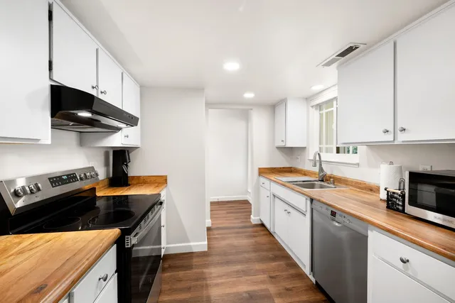 a kitchen with stainless steel appliances a sink a stove and cabinets