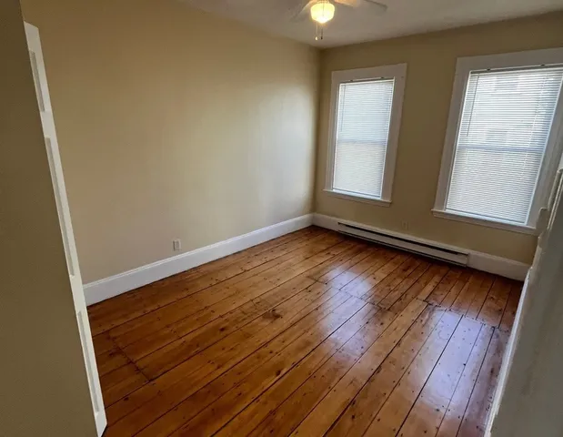 a view of an empty room with wooden floor and window