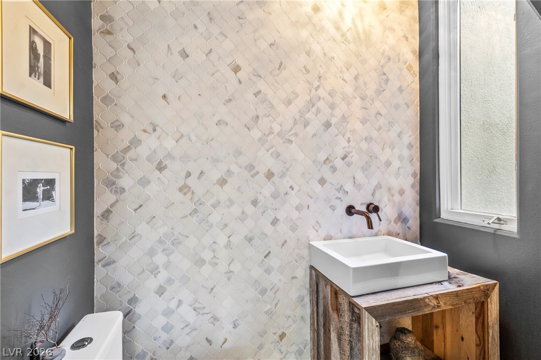 2000 Grouse Street Las Vegas, NV 89134 - Photo 9 of 89 A stylish half bath showcasing intricate tiled walls and a modern vessel sink set atop a rustic wooden vanity.