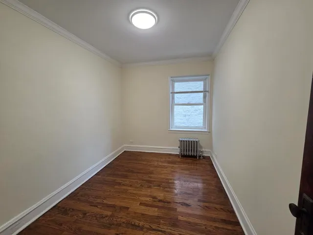 an empty room with wooden floor cabinet and windows