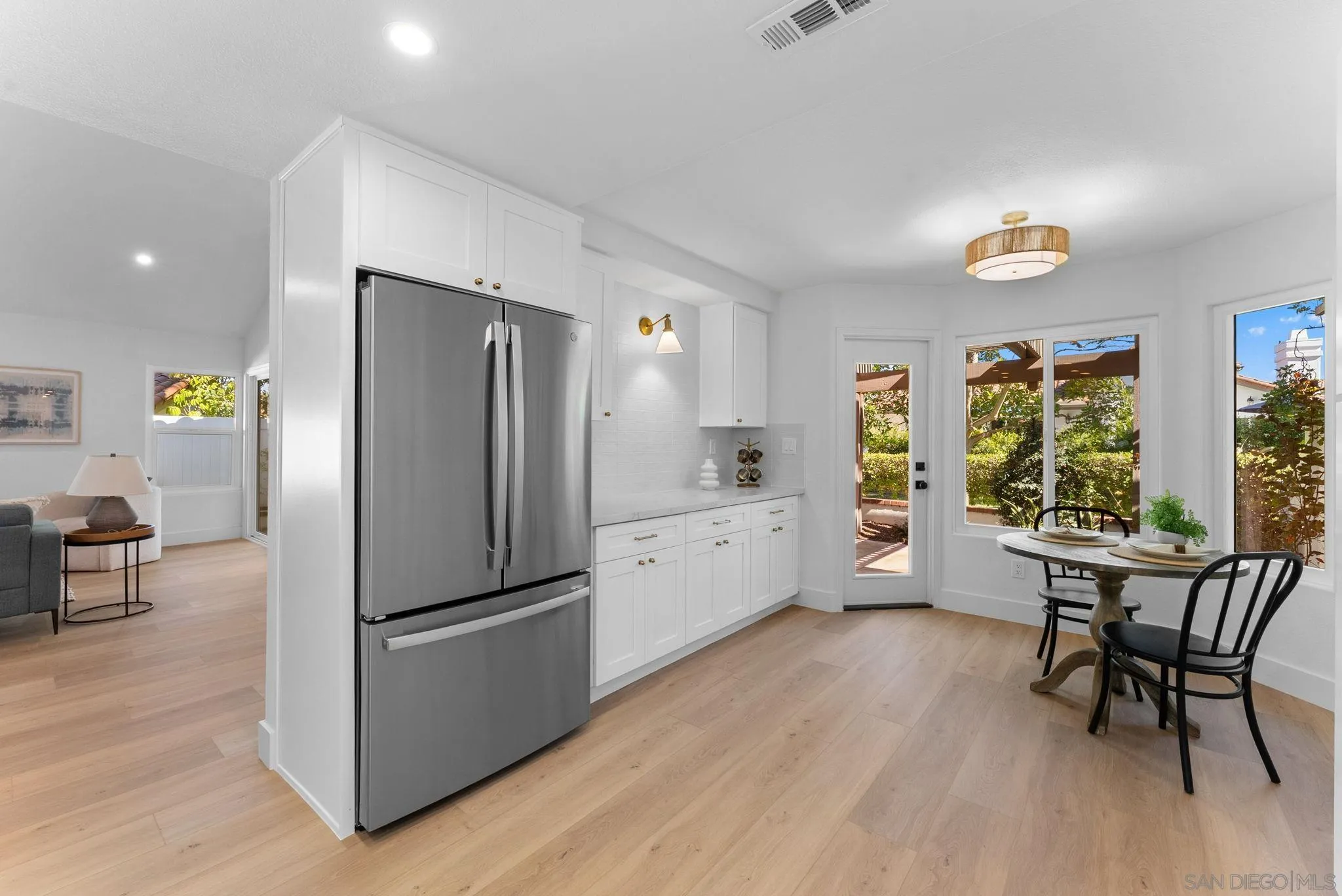 4946 Alicante Way Oceanside, CA 92056 - Photo 11 of 34 a kitchen with stainless steel appliances a refrigerator a stove a dining table and chairs with wooden floor