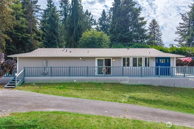 a view of a house with a yard plants and large trees with wooden fence