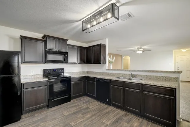 a kitchen with stainless steel appliances granite countertop a sink stove microwave and refrigerator