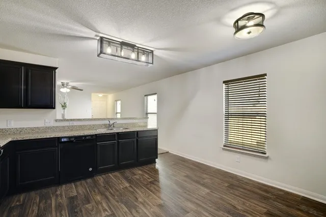 a kitchen with stainless steel appliances granite countertop a sink cabinets and wooden floor