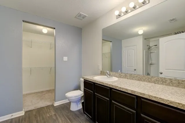 a bathroom with a granite countertop sink a toilet and shower