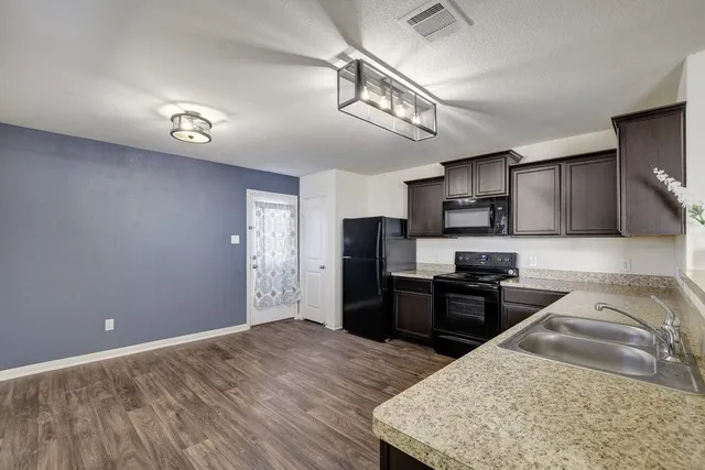 a kitchen with granite countertop a refrigerator stove top oven and sink