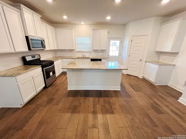 a large kitchen with cabinets wooden floor and stainless steel appliances