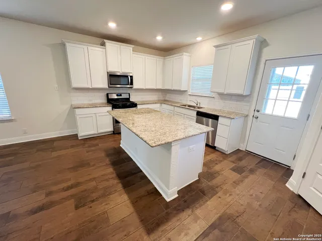 a kitchen with granite countertop white cabinets and white appliances