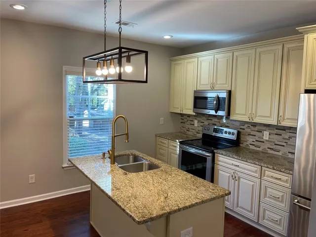 a kitchen with granite countertop stainless steel appliances a stove microwave and sink