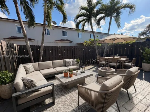 a view of a patio with couches a table and chairs and potted plants