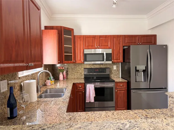 a kitchen with stainless steel appliances granite countertop a refrigerator a stove top oven and a sink