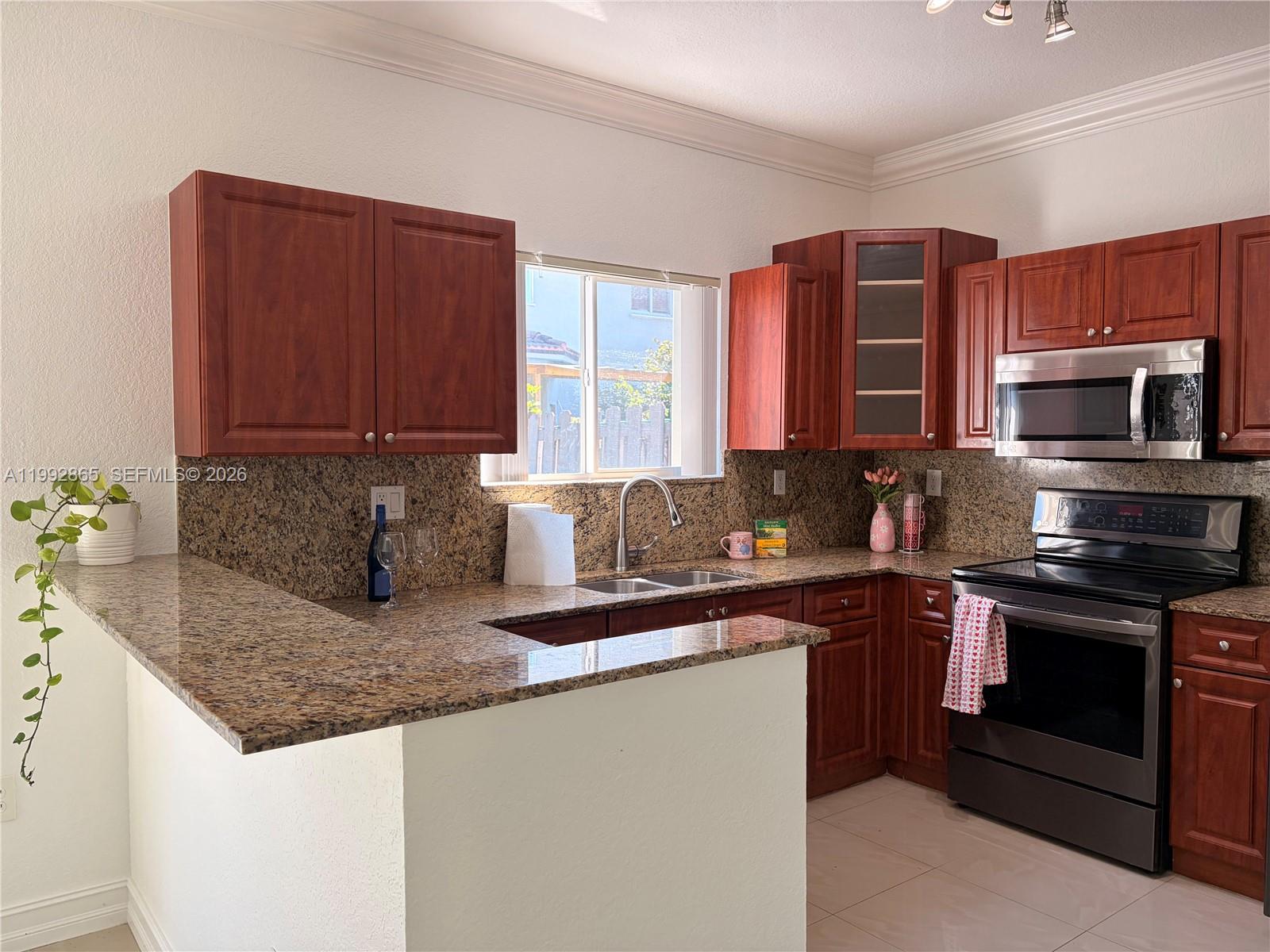 14738 Southwest 22nd Terrace Miami, FL 33185 - Photo 10 of 46 a kitchen with stainless steel appliances granite countertop a sink stove and microwave