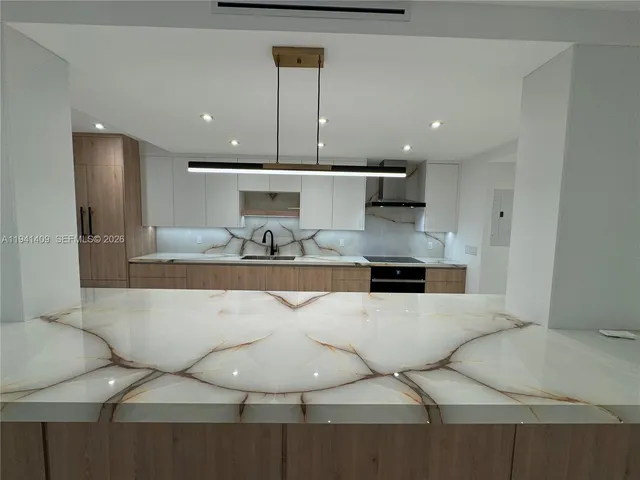 a large kitchen with kitchen island a large counter top a sink a stove and a refrigerator