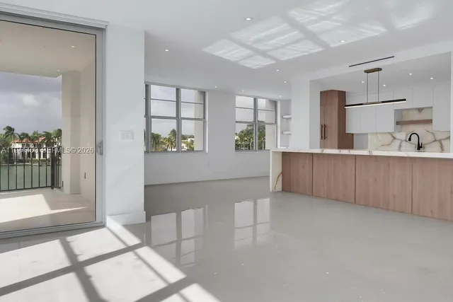 a large white kitchen with kitchen island granite countertop a refrigerator and a sink