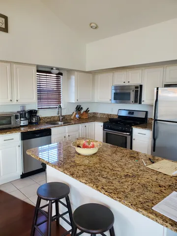 a kitchen with a stove a sink a kitchen island and chairs