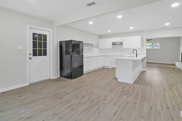 a large kitchen with a wooden floor and stainless steel appliances
