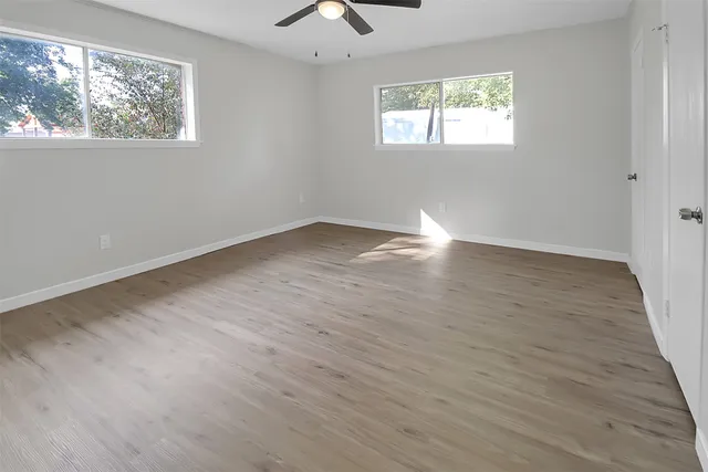 a view of empty room with wooden floor and fan