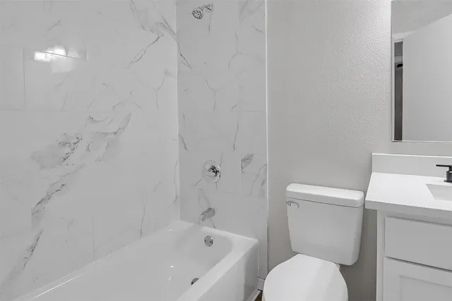 a white toilet sitting next to a bath tub