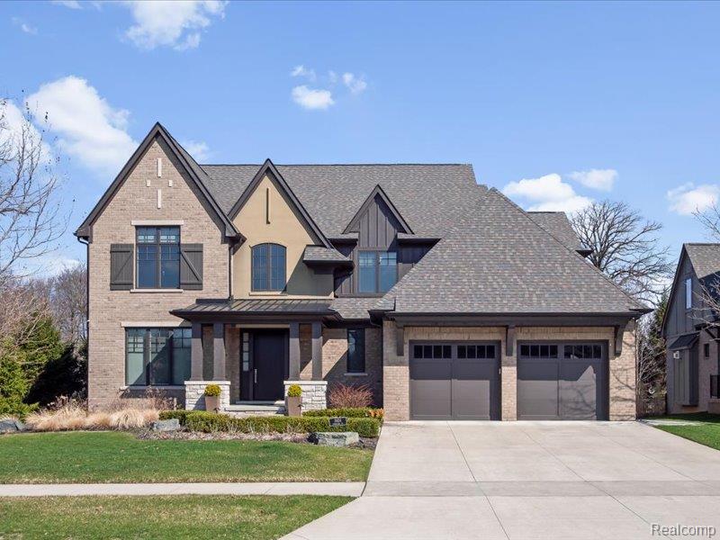 View of front of property with brick siding, a front yard, and an attached garage