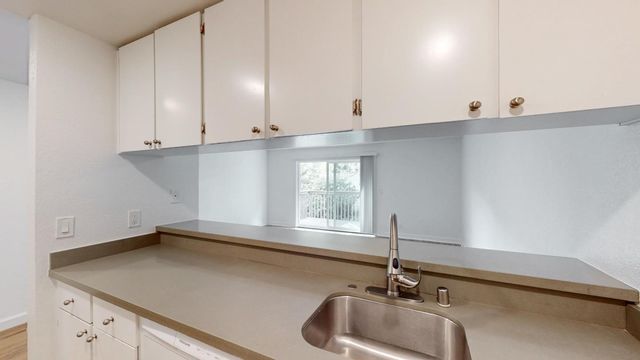 a kitchen with granite countertop white cabinets and a sink