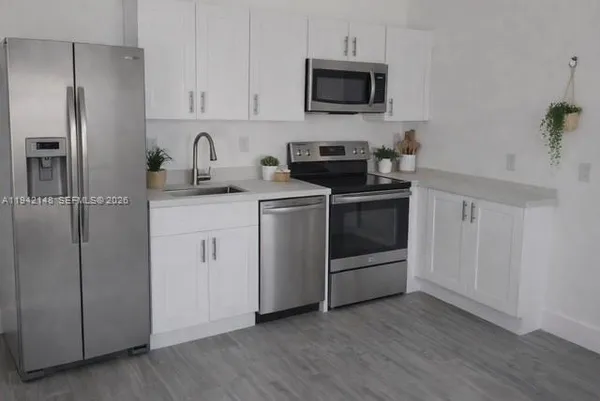 a kitchen with cabinets stainless steel appliances and wooden floor