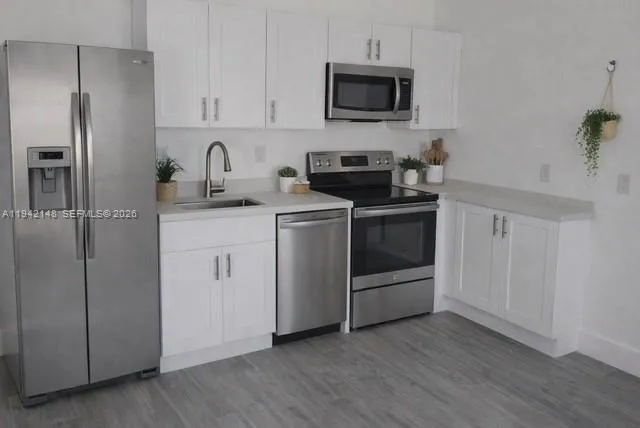 a kitchen with cabinets stainless steel appliances and wooden floor