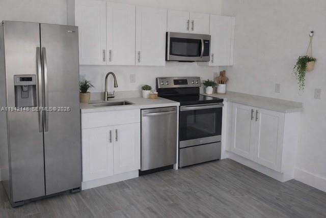 6875 Northwest 4th Avenue, Unit B Miami, FL 33150 - Photo 1 of 5 a kitchen with cabinets stainless steel appliances and wooden floor