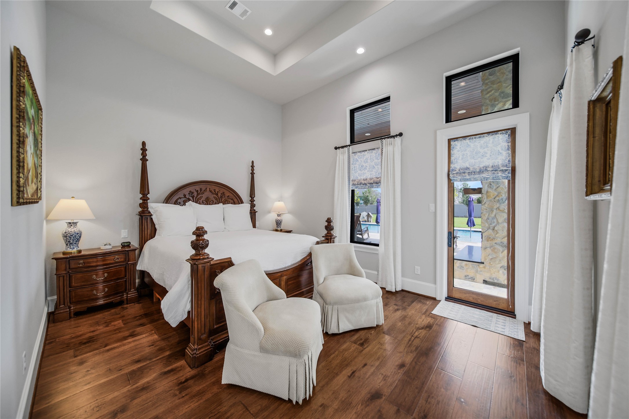 24718 Shadow Pond Spring, TX 77389 - Photo 21 of 49 Elegant bedroom with rich hardwood flooring, a stately four-poster bed, and abundant natural light from large windows and a glass door leading to the patio.