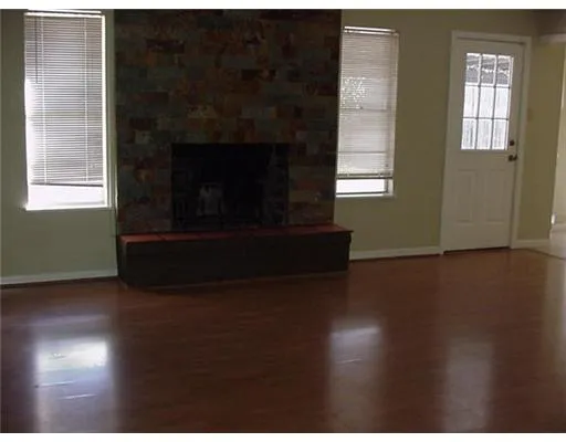 a living room with wooden floor and a fireplace
