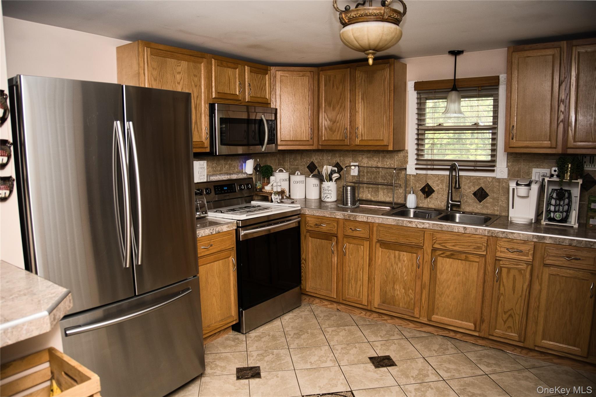 165 Lattintown Road, Unit 75 Newburgh, NY 12550 - Photo 6 of 24 Kitchen with appliances with stainless steel finishes, brown cabinets, tasteful backsplash, light tile patterned floors, and lots of cabinets.