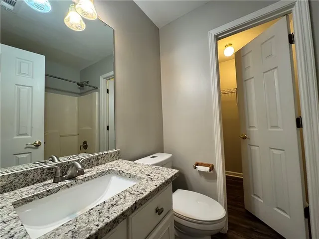 a bathroom with a granite countertop sink toilet and a mirror