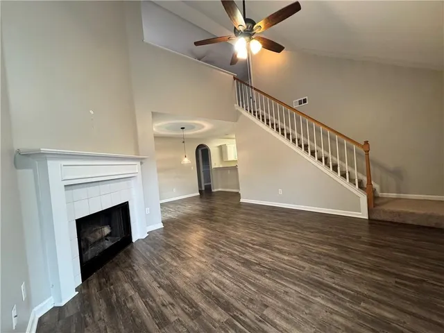a view of an empty room with wooden floor a fireplace and a window
