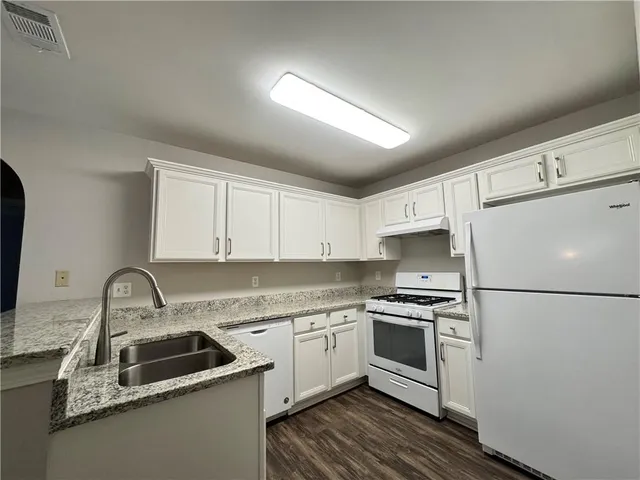 a kitchen with a sink a refrigerator and white cabinets