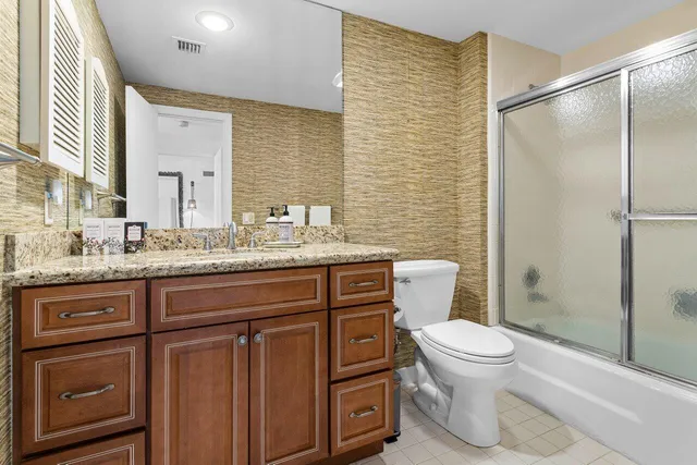 a bathroom with a granite countertop sink toilet and shower