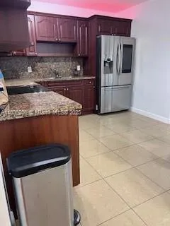 a kitchen with granite countertop a stove and a refrigerator with wooden cabinets