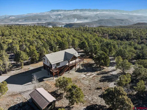 an aerial view of a house with a yard and mountain view in back