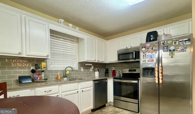 a kitchen with stainless steel appliances granite countertop a refrigerator a sink a stove a microwave and wooden cabinets