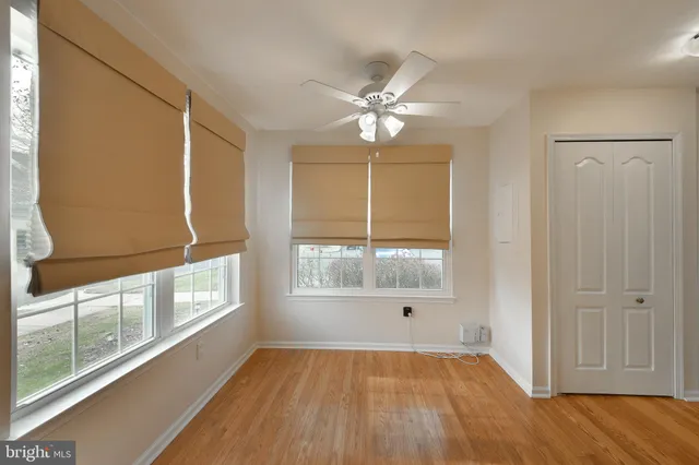 an empty room with wooden floor fan and windows