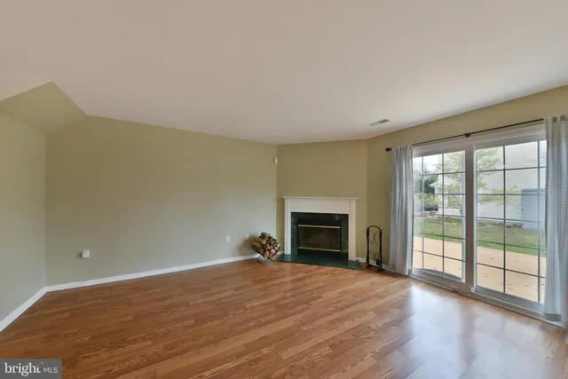 a view of empty room with wooden floor and fireplace