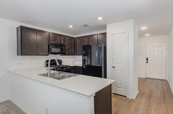 a kitchen that has a refrigerator a sink and cabinets