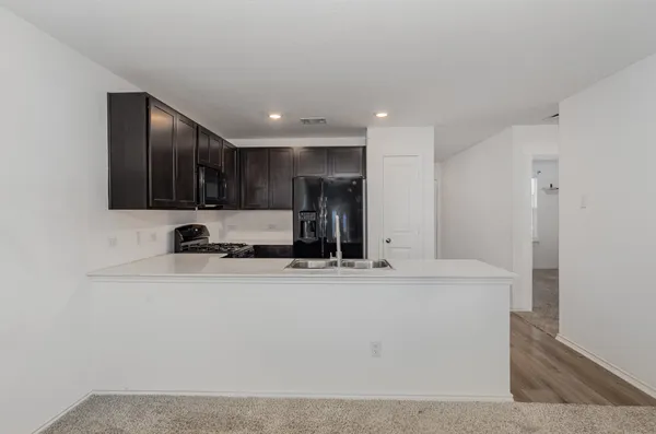 a view of a kitchen with stainless steel appliances granite countertop a refrigerator a sink and a stove