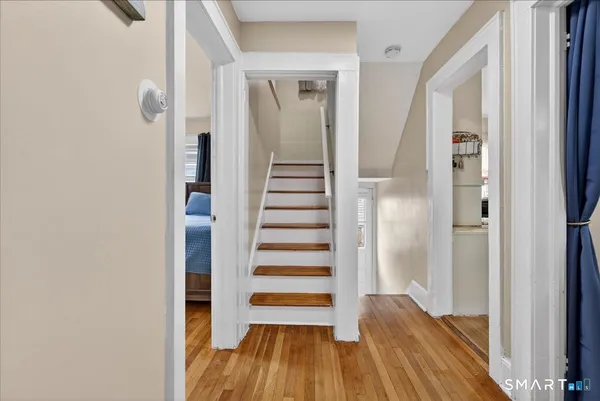a view of a hallway with wooden floor and a bathroom