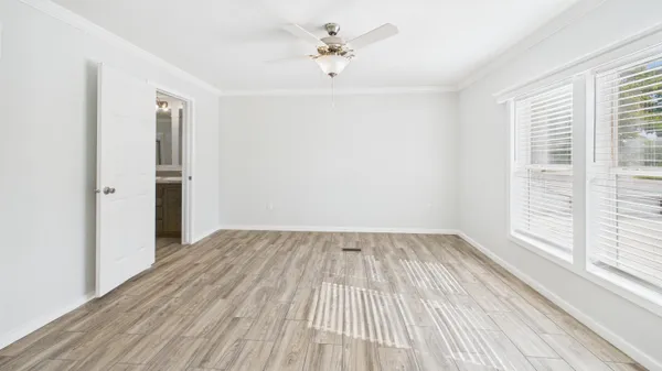 an empty room with wooden floor ceiling fan and windows