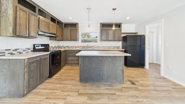 a kitchen with stainless steel appliances granite countertop a stove top oven a refrigerator a sink and dishwasher with wooden floor