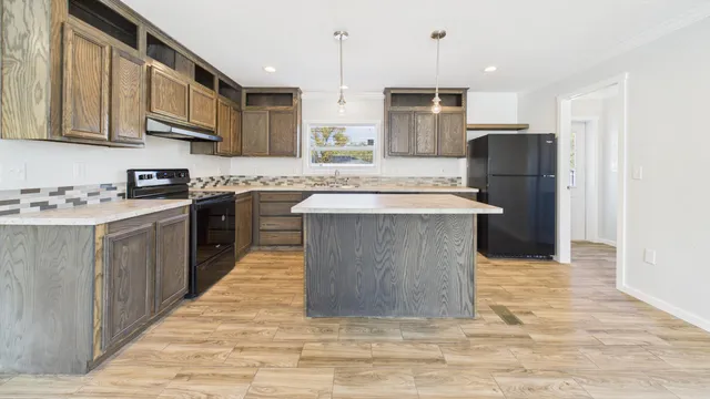 a kitchen with stainless steel appliances granite countertop a stove top oven a refrigerator a sink and dishwasher with wooden floor