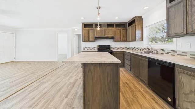 a large kitchen with stainless steel appliances kitchen island granite countertop a sink stove and cabinets