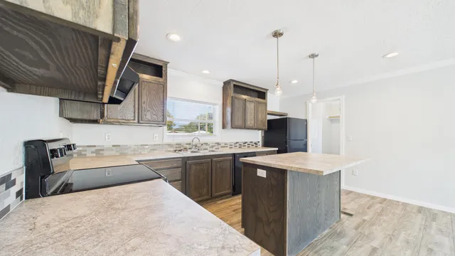 a kitchen with stainless steel appliances kitchen island granite countertop a sink stove and refrigerator